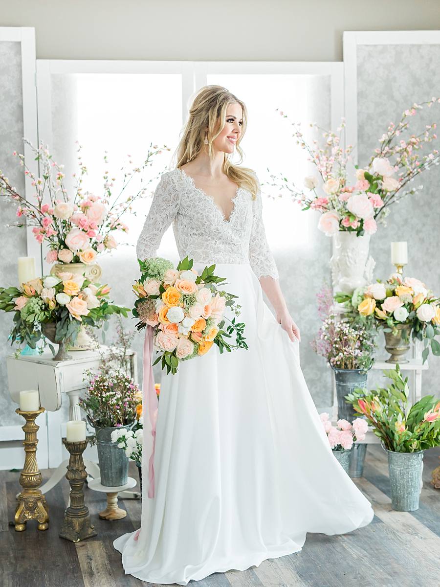 Bride in her wedding dress surrounded by pastel flowers