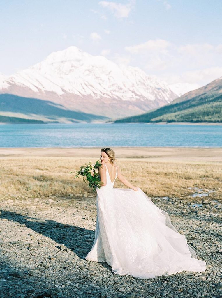 Alaska wedding portraits with bride walking along the shoreline of Eklutna Lake