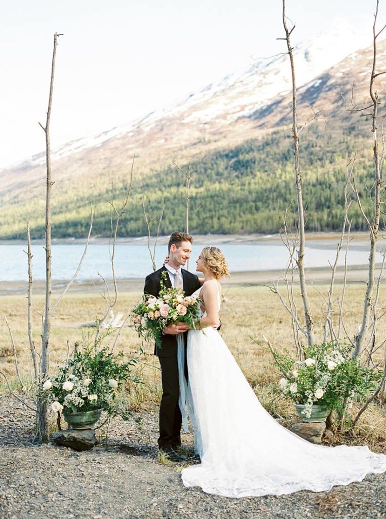 Destination bride and groom saying their wedding vows overlooking the beautiful Alaska mountains and Eklutna lakeside views