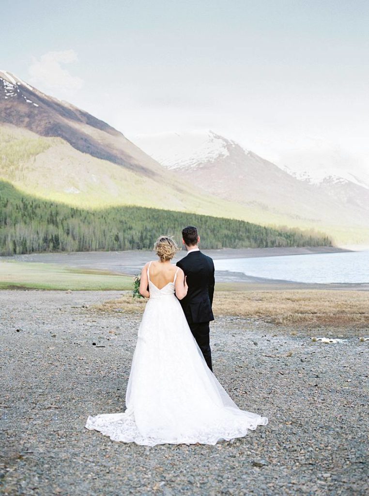 Bride and groom walking along Eklutna Lake shore in Alaska by Rachel Tweggs Photography