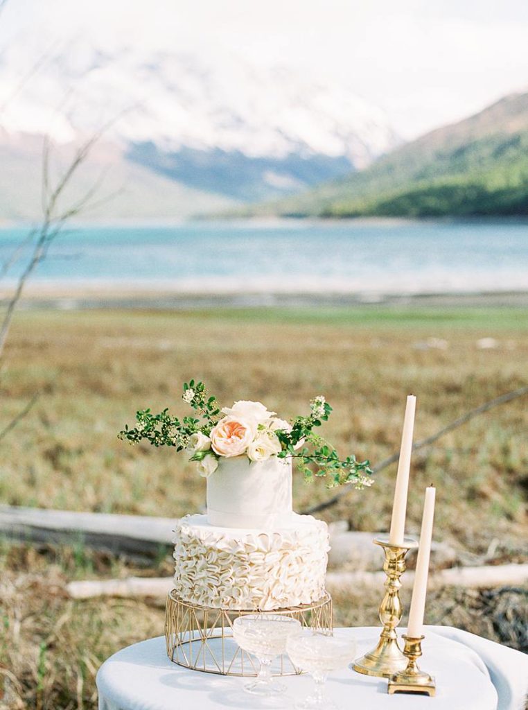 Wedding cake on table with candles and mountains in the background